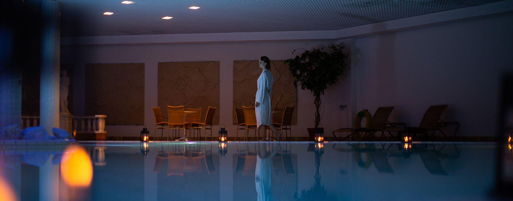 A woman walks beside a candlelit pool at Naantali Spa Hotel and Resort.