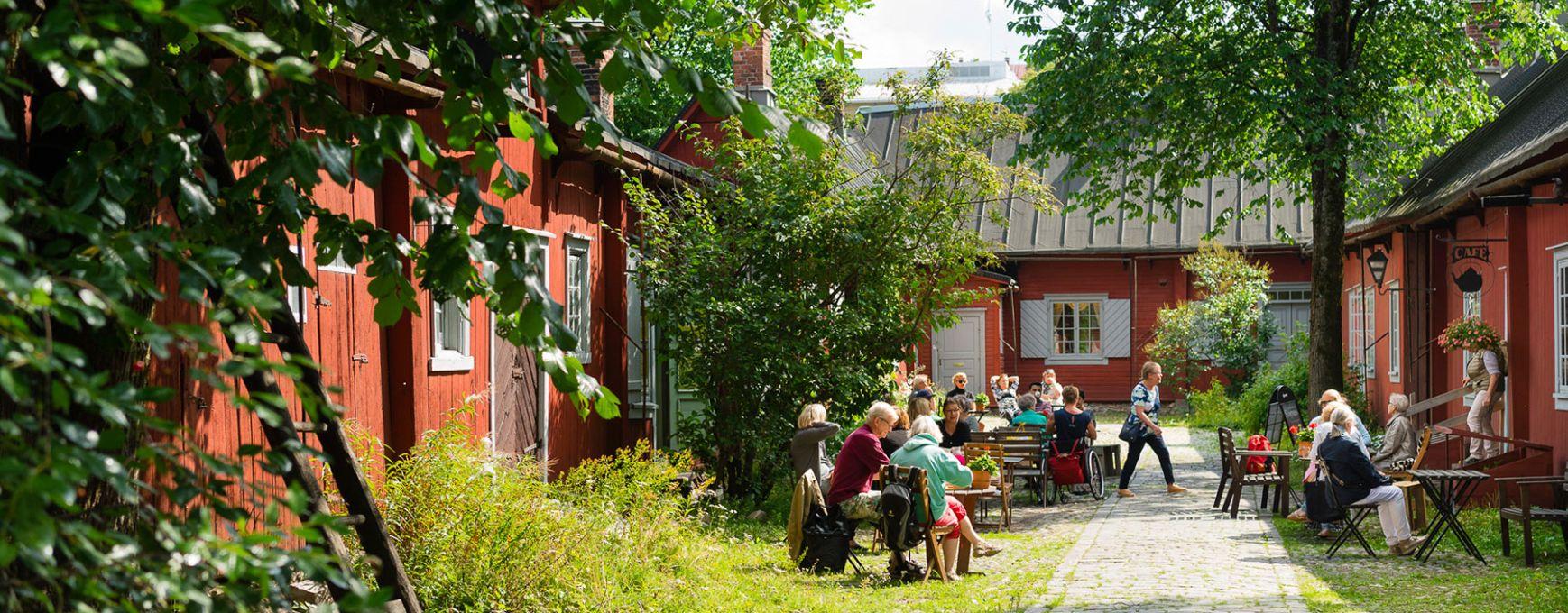 Visitors sit in Cafe Qwensel's outside garden, enjoying coffee and cake.