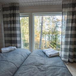 A bedroom at a cottage at Söderlångvik Manor, featuring a double bed and a window that overlooks the forest.