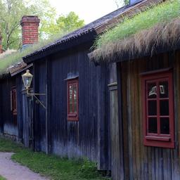 A row of old wooden buildings with grass-topped roofs at Luostarinmäki.